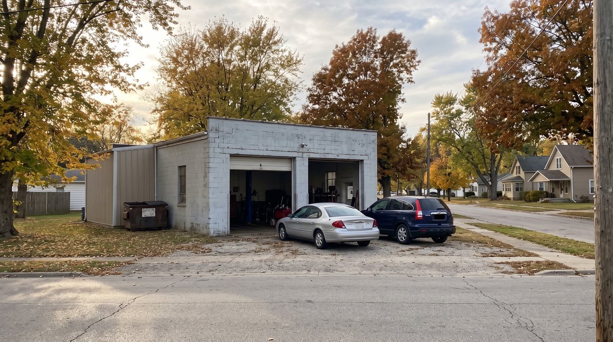 A small independent auto repair shop with service bay doors and customer cars parked out front